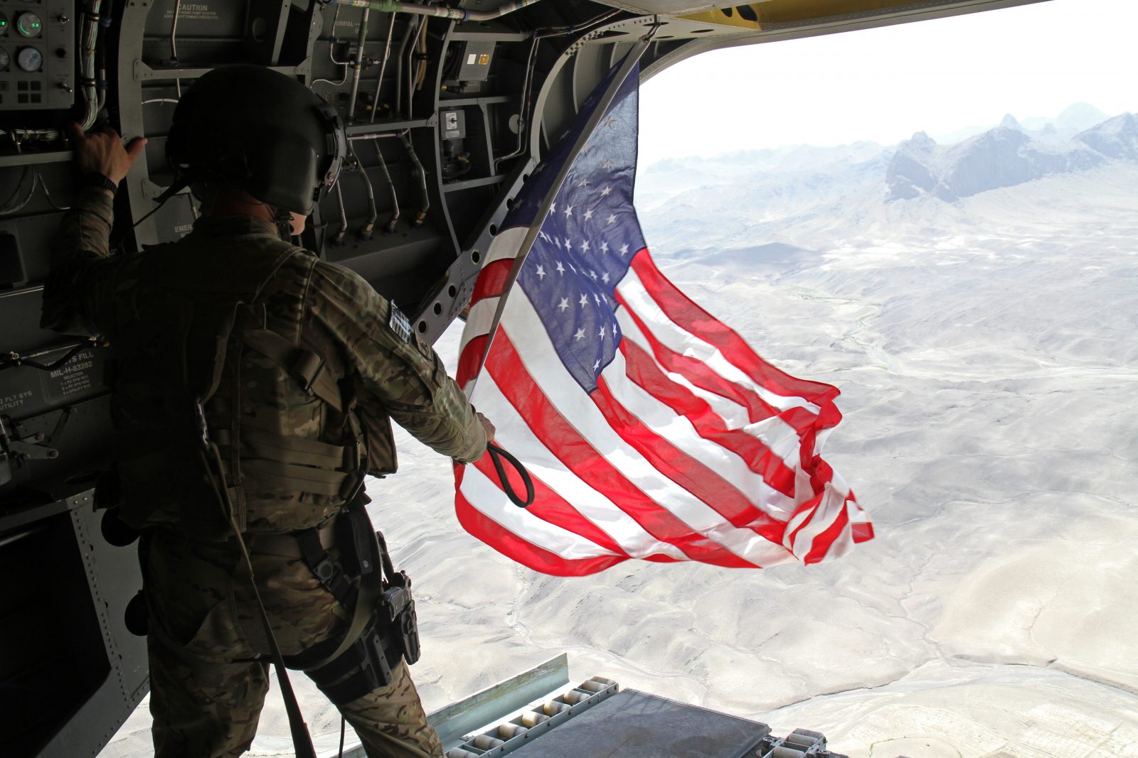 soldier flying U.S. flag from helicopter